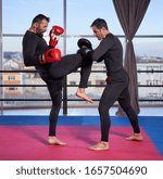 Kickboxer hitting pads with his coach in the gym