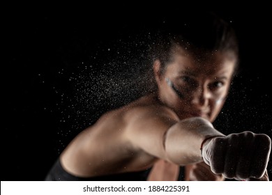 Kickboxer kirl with magnesium powder on her hands, punching with dust visible.