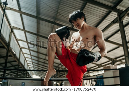 Kickboxer in the ring with the copyspace do stretches before the fight makes swing movements with his knee