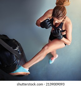 Kicking Things Up A Notch. High Angle Shot Of A Female Kickboxer Working Out With A Punching Bag.