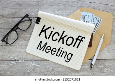 Kickoff Meeting Text On An Open Notebook On An Envelope With Money, Business And Financial Concept