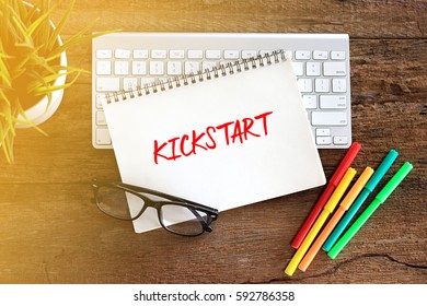KICKSTART Concept words on notebook with keyboard and glasses on rustic wooden table