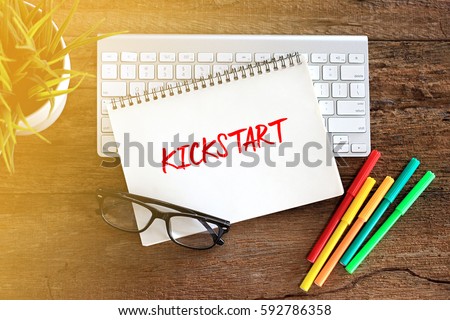 KICKSTART Concept words on notebook with keyboard and glasses on rustic wooden table