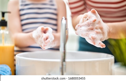 Kid and adult are washing their hands. Protection against infections and viruses. Close up.   