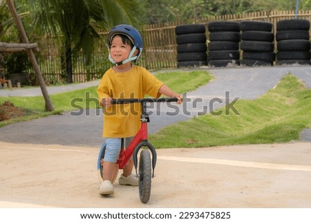 Kid Asian Baby Boy wearing safety bike helmet playing Scooter or Balance bike in the playground
