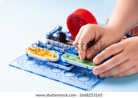 Kid assembling educational electronic circuit board toy, learning basics of electricity, conductors and circuits, STEM education concept