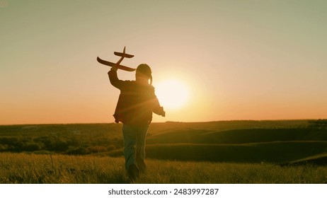 Kid aviator dreams of flying and becoming pilot. Little girl child wants to become pilot and astronaut. Slow motion. Happy girl runs with toy airplane on field in sunset light. Child play toy airplane - Powered by Shutterstock