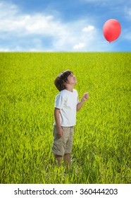 Kid with balloon standing on beautiful meadow