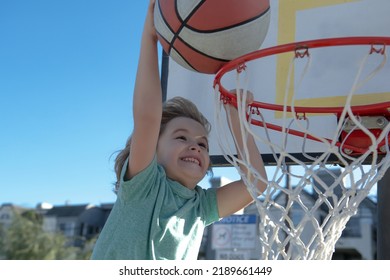 Kid Boy Basketball Player With A Ball Scoring A Goal. Child Player Scoring Slam Dunk, Stock Photo.