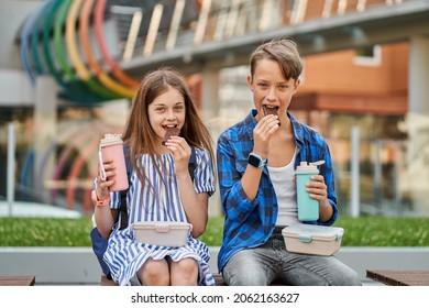 Kid Boy And Kid Girl Eating Chocolate And Drink Tea With Lunchbox And Thermos.