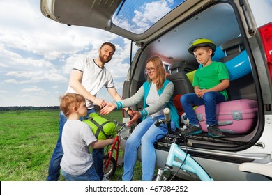 Kid Boy Helping His Parents To Load Their Car Boot