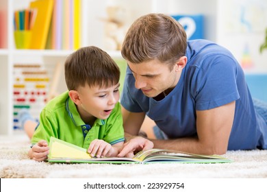 Kid Boy And His Father Read A Book On Floor At Home