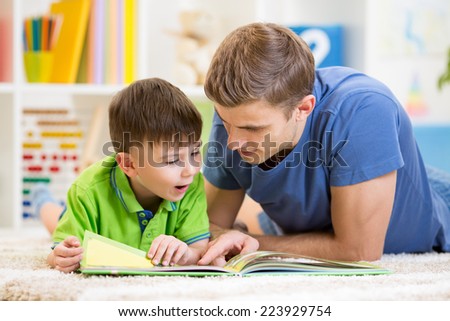 kid boy and his father read a book on floor at home