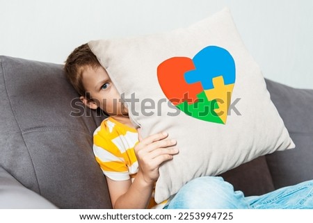 Kid boy holding pillow with puzzle heart, child mental health concept, world autism awareness day, teen autism spectrum disorder awareness concept
