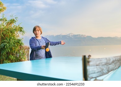 Kid boy playing  ping pong by the lake, active lifestyle for children - Shutterstock ID 2254691233