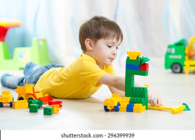 kid boy playing toy blocks on floor at home
