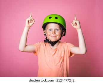 Kid Boy In Protect Sport Helmet Pointing Up Above His Head. Child In Green Safety Cap Ready For Sport School Lesson. Sport Equipment.