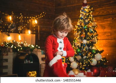 Kid Boy Santa Hold Christmas Gift Red Sock. Childhood Moments. Christmas Stocking Concept. Child Cheerful Face Got Gift In Christmas Sock. Check Contents Of Christmas Stocking. Joy And Happiness.