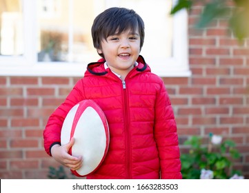 Kid boy with smiling playing rugby in sunny day morning, Child get ready for practicing rugby ball during a school session,Spring or Summer sport for young children - Powered by Shutterstock