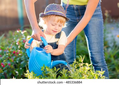 Kid boy toddler helping mother in the garden sunny summertime
