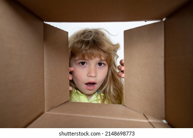 Kid Boy Unpacking And Opening Carton Box Looking Inside With Surprise Face. Kid Opening Package.