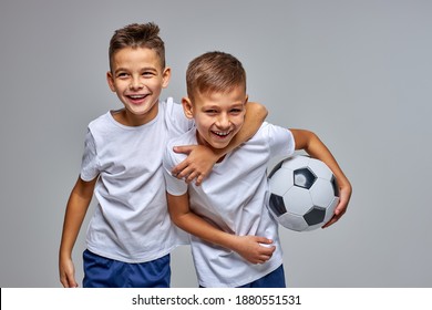 kid boys go in for soccer sport professionally, stand hugging each other, have fun, smile at camera, holding ball in hands, isolated portrait - Powered by Shutterstock