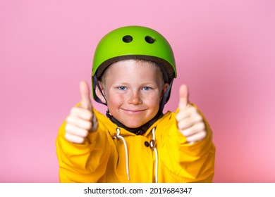 Kid With Bright Green Protect Helmet And Sunglasses And Yellow Coat Showing Thumbs Up. Funny Face Of Blond Freckled Child Boy. Extreme Sport For Children. Protect Equipments For Safety. Life Insurance