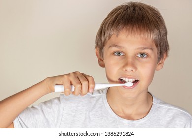 Kid Brushing Teeth With White Electric Toothbrush