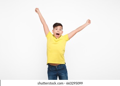 Kid in casual clothing looking happily at camera and holding hands up on white. 