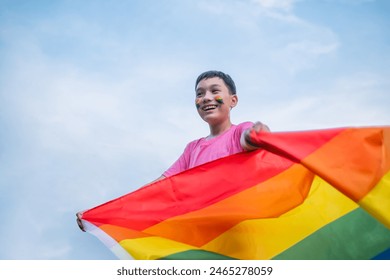 Kid celebrating pride month holding LGBTQ flag smiling cheerful happiness, celebrating freedom of gay , transgender, bisexual lesbian and gay communities. White sky clouds background. - Powered by Shutterstock