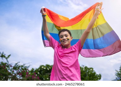 Kid celebrating pride month holding LGBTQ flag smiling cheerful happiness, celebrating freedom of gay , transgender, bisexual lesbian and gay communities. White sky clouds background. - Powered by Shutterstock