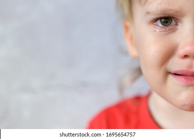 Kid Crying. The Face Of A Cute Little Upset Four Year Old Baby Boy In Tears. Children's Grief. Gray Concrete Wall Background. Space For Text