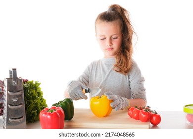 A Kid Cutting Vegetables With A Knife Wearing Safety Gloves In A Kitchen