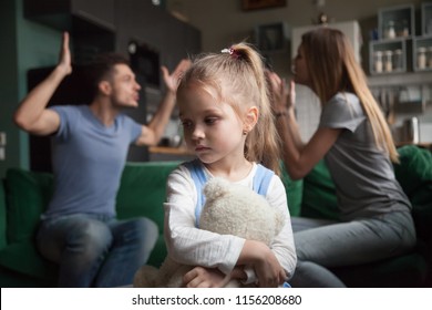 Kid daughter feels upset while parents fighting at background, sad little girl frustrated with psychological problem caused by mom and dad arguing, family conflicts or divorce impact on child concept