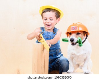 Kid And Dog Wearing Hardhats Working With Saw And Hammer At Construction Site