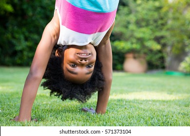 A Kid Doing A Headstand In Garden