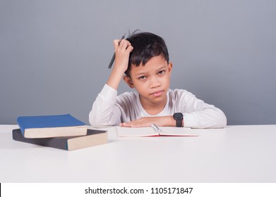 Kid Doing Homework At His Study Table With Stress Face Action.Kid Got Problem With Homework.Lazy Kid At Study Table.