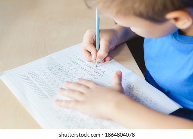 Kid Doing Lesson At Home. Child Boy Writing In Worksheet With Pencil. Children Education Concept