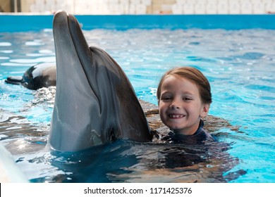 Kid and Dolphin. Girl swimming and hugging with bottlenose Dolphin in blue water. Dolphin Assisted Therapy
