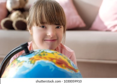 Kid with down syndrome looking at camera over globe
