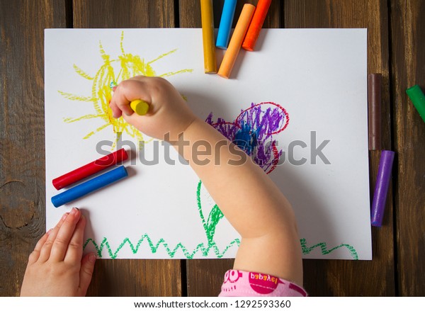kid drawing on wooden\
table