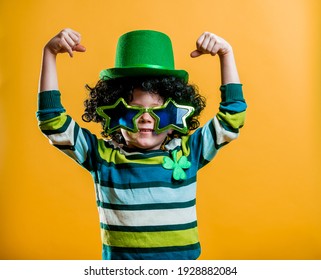 Kid dressed in green with St. Patrick's hat and glasses and clover leaf. Patrick party with Irish culture and traditions. Bright child boy at school. Happy strong boy.