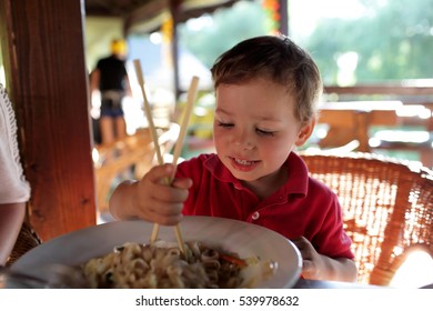 The Kid Eating Noodles In An Asian Restaurant