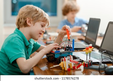 Kid enjoys building a robot. Young student putting a control board and fixing it with screws.