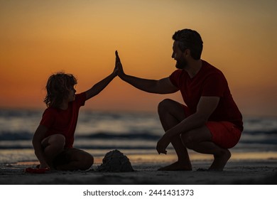 Kid and father building sandcastle. Father and son playing on the beach. Father and child son on tropical beach on sunset. Sand castle. Father with son on the sea. Fathers giving Five hand. - Powered by Shutterstock