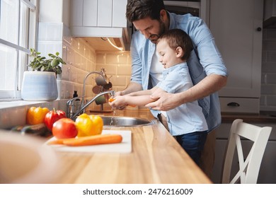 Kid, father and washing vegetables for cooking organic food, nutrition or learning healthy diet. Dad, happy child or cleaning carrot in kitchen for hygiene, wellness or teaching boy meal prep in home - Powered by Shutterstock