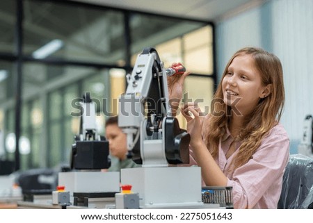 Kid female teen child enjoy Machine Learning Robot arm is Moving Under Control robot at technology class, stem education robot arms for digital automation software for artificial intelligence ai