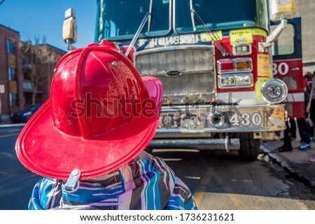 Kid with a fire fighter helmet in front of a fire truck in Montreal, Canada