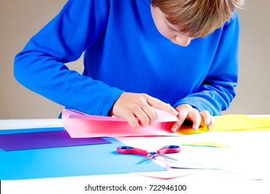 Kid Folding Colored Paper And Making Origami.