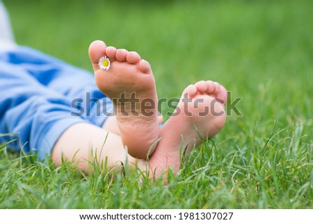 Kid foot on green grass on garden. Barefoot concept, freedom, relax and healthy feet. 